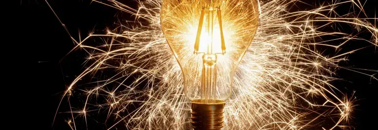 Light bulb against a dark background with light beams scattered around